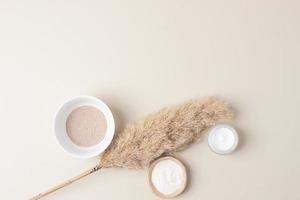 Natural background with skin care products and pampas dry grass on pastel beige. Flat lay, copy space photo