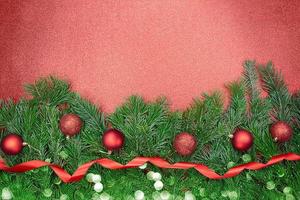 Fir branches with red shiny and matte balls, ribbon with bokeh on sparkling background. Christmas, New Year. Copy space photo