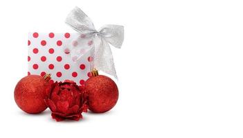 Gift box with polka dots and silver bow with red shine toys. New Year or Christmas congratulations composition on white background. Banner. Copy space photo