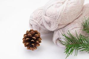 Balls of gray yarn, pinecone, spruce branch on a white background. Knitting, sewing, needlework, hobby, leisure. Copy space photo