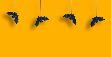 Horizontal pattern. Black bats in row are suspended with spread wings on yellow orange background. Hallowen. Copy space photo