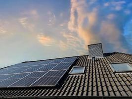 Solar panels producing clean energy on a roof of a residential house photo