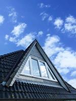 Roof window in velux style with black roof tiles. photo
