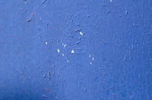 Photo of old and peeled blue plaint cracked plaster wall surface close up as art background and texture.