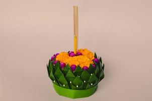 krathong de hoja de plátano que tiene 3 varitas de incienso y velas decoradas con flores para la luna llena de tailandia o el festival loy krathong sobre fondo rosa. foto