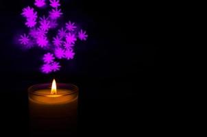 Aromatic candle with flame and snowflake shape bokeh on dark background for Thanks giving and Christmas day. photo