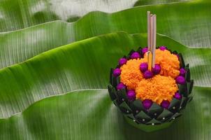 krathong de hoja de plátano que tiene 3 varitas de incienso y velas decoradas con flores para la luna llena de tailandia o el festival loy krathong que se pone en hojas de plátano verde. foto