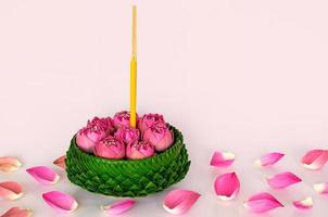 Banana leaf Krathong decorates with pink lotus flowers and petals for Thailand full moon or Loy Krathong festival on pink background.