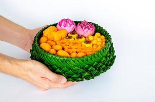 Hand holding partial focus of Thai wedding desserts on banana leaves plate or krathong for thai traditional ceremony on white background. photo