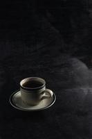 una taza de café caliente sobre un fondo negro. escena oscura maqueta de espacio de banner para agregar texto foto