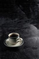 una taza de café caliente sobre un fondo negro. escena oscura maqueta de espacio de banner para agregar texto foto