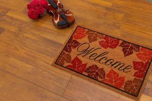 New Delhi, Delhi, IN, 2022 - Beautiful Colorful Leaf Printed Welcome zute doormat placed on brown floor with Guitar photo