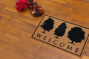 New Delhi, Delhi, IN, 2022 - Beautiful welcome doormat peach color with black tree placed on brown floor with Guitar photo