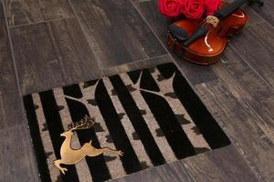 New Delhi, Delhi, IN, 2022 - Beautiful Black Gold Welcome zute doormat with trees and deer placed on brown floor with Guitar photo