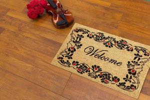 New Delhi, Delhi, IN, 2022 - Beautiful welcome peach color coir doormat with flower border placed with Guitar and Red Roses photo
