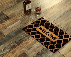New Delhi, Delhi, IN, 2022 - Modern honeycomb patterned yellow black welcome zute doormat placed with Whiskey and Glass photo