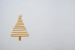 árbol de navidad hecho de galletas de pajitas de pepero, sobre textura de fondo blanco. vista superior con espacio para texto a la derecha foto