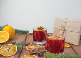 vino tinto caliente de navidad con especias y frutas en una mesa rústica de madera. bebida caliente tradicional en navidad foto