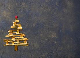 árbol de navidad hecho de galletas de pajitas de pepero, sobre fondo de textura negra. vista desde arriba. foto