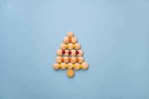 Christmas tree made of cookies and sweets on a blue background with space for text. Christmas baking concept. photo