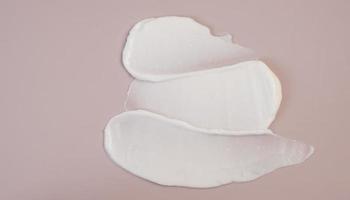 loción de crema de belleza blanca mancha de muestra de frotis de resaltado sobre fondo rosa foto