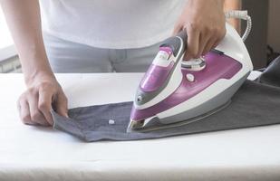 primer plano mano de mujer planchando ropa falda azul en la tabla de planchar. foto