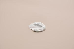 The texture of white delicate cream on a beige background. photo