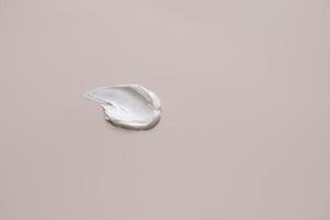 The texture of white delicate cream on a beige background. photo