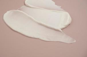 White beauty cream lotion highlighter smear swatch smudge on pink background photo