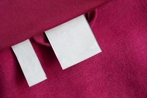 Blank white laundry care clothes label on red fabric texture background photo