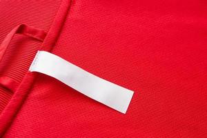 White blank clothes label on red jersey texture background photo