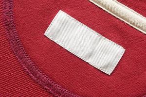 Blank white laundry care clothes label on red fabric texture background photo