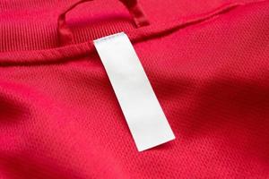 etiqueta de ropa blanca en blanco sobre fondo de textura de jersey rojo foto