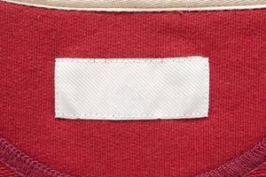 Blank white laundry care clothes label on red fabric texture background photo