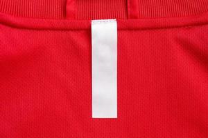 White blank clothes label on red jersey texture background photo