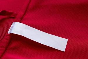 White blank clothes label on red jersey texture background photo