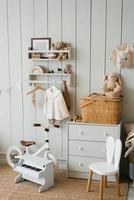 acogedor interior de una habitación infantil, una zona de juegos. juguetes, una bicicleta, un piano, una cómoda y ropa en una percha. apartamento de estilo escandinavo foto