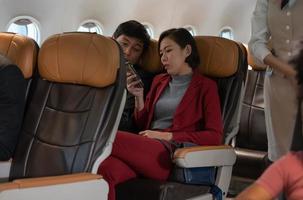 Couple passengers looking at cellphone on board in plane during their flight photo