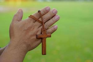 wooden cross holding in hands of an Asian man, concept for hope, love, forgiveness and belief in Jesus around the world. Soft and selective focus. photo