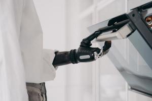 Person with disability, cook opening oven, using bionic prosthetic arm, preparing dinner in kitchen photo