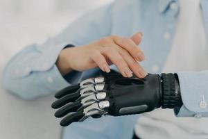 Female turns on high tech prosthetic hand, artificial limb. Advertising of bionic prosthesis photo