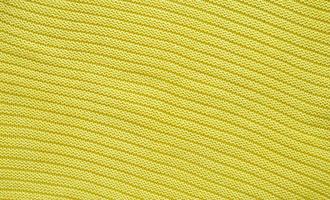 Texture of smooth knitted yellow sweater with pattern. Top view, close-up. Handmade knitting wool or cotton fabric texture. Background of knitting patterns. photo