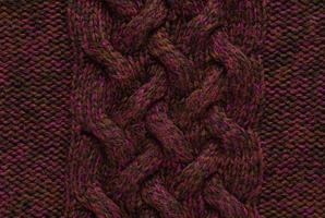 Texture of smooth knitted dark sweater with pattern. Top view, close-up. Handmade knitting wool or cotton fabric texture. Background of knitting patterns with a vertical large Braid Cable. photo