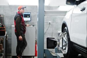 Auto mechanic sets american SUV car for diagnostics and configuration camber check in workshop of service station.. photo