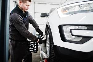 Auto mechanic sets american SUV car for diagnostics and configuration camber check in workshop of service station.. photo