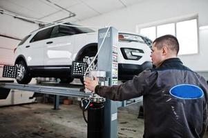 Auto mechanic sets american SUV car for diagnostics and configuration camber check in workshop of service station.. photo