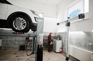 coche todoterreno americano en soporte para verificación de inclinación de alineación de ruedas en el taller de la estación de servicio. foto
