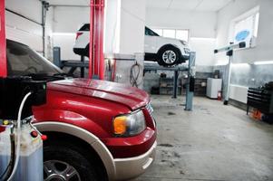 Two american SUV car on stand for wheels alignment camber check in workshop of service station. photo