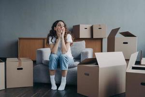 Tired divorced girl sitting with cardboard boxes on relocation day. Moving to rented house, eviction photo
