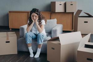 Exhausted upset woman sitting with cardboard boxes on relocation day. Financial problem, eviction photo